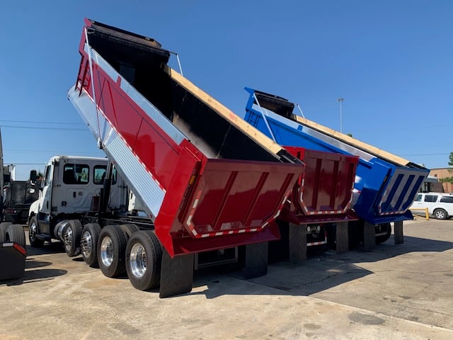 back of three dump trucks